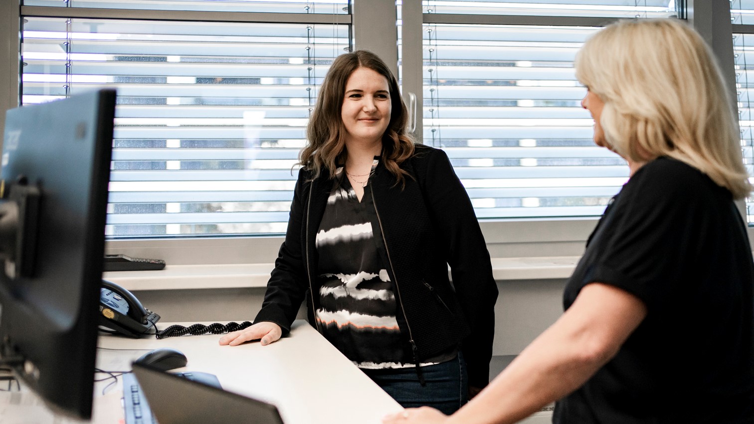 Zwei Frauen führen ein Beratungsgespräch am Schreibtisch.